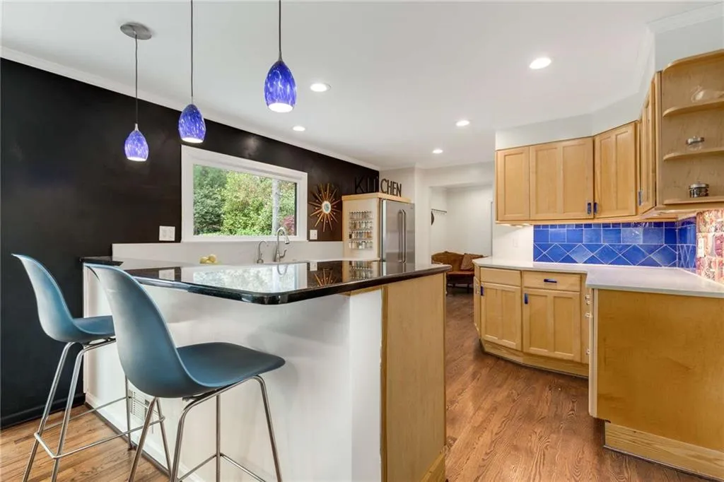 Kitchen with high end refrigerator, a breakfast bar, a sink, and wood finished floors