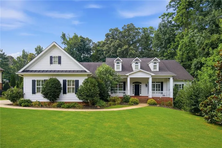 White siding residence with a dark roof and prominent dormer windows