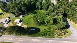 Expansive lot featuring mature trees, a manicured lawn, and paved road frontage
