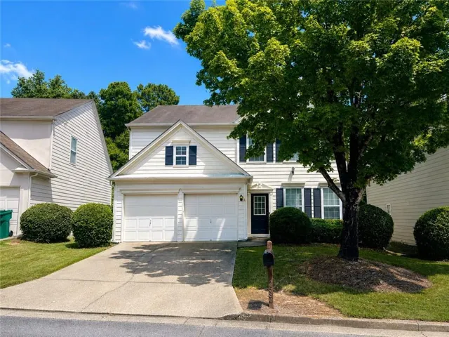 Two-story exterior with light-colored siding, contrasting dark shutters, and a two-car garage