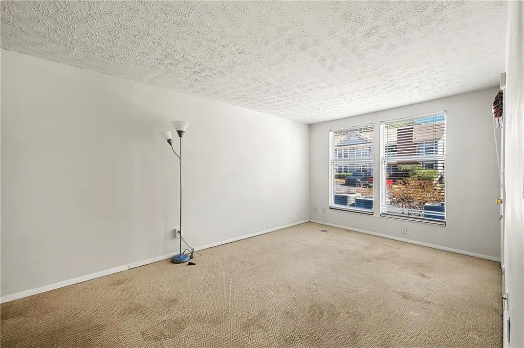 Spare room featuring a textured ceiling, carpet, and baseboards
