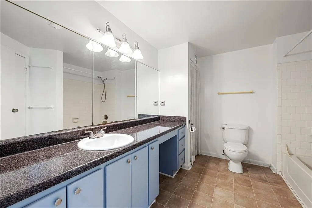 Bathroom featuring vanity, tile patterned flooring, toilet, and baseboards