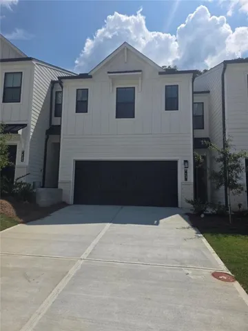 Contemporary townhome exterior with white vertical and horizontal siding, a two-car garage, and a concrete driveway