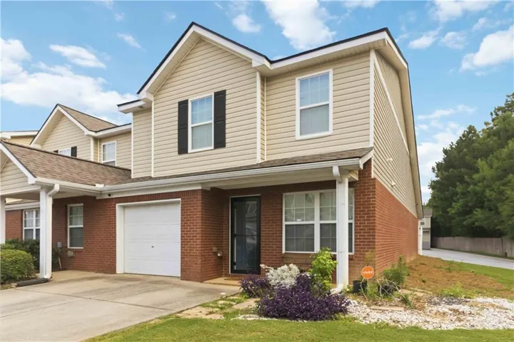 Two-story townhome featuring a brick and siding exterior, an attached garage, covered entryway, and a sloped roof