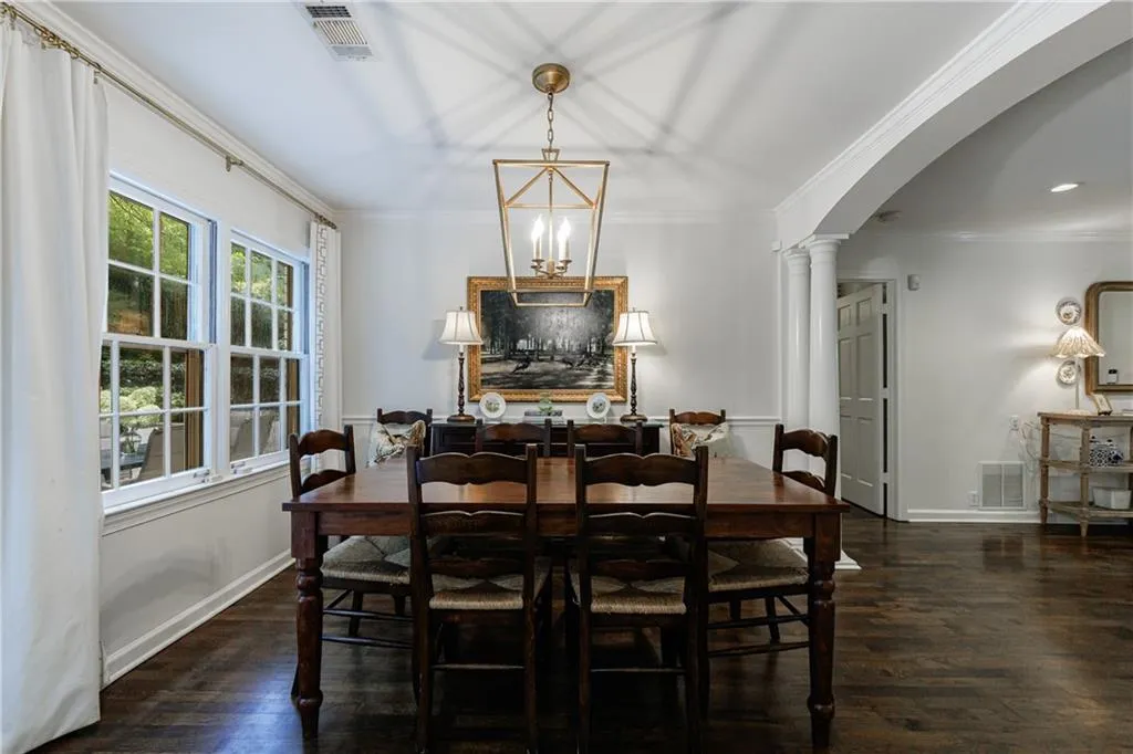 Dining room with arched walkways, decorative columns, wood finished floors, and ornamental molding
