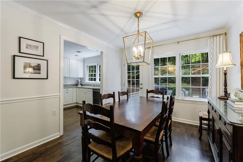 Dining area with dark wood-style floors, a chandelier, and ornamental molding