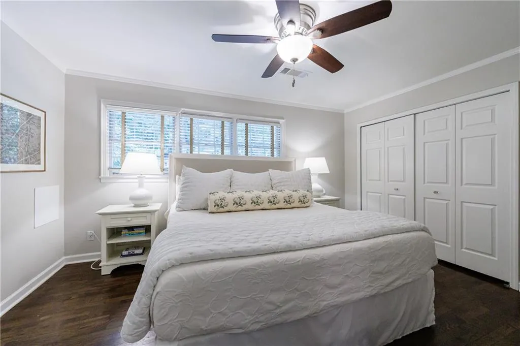 Bedroom featuring wood finished floors, a closet, ornamental molding, and a ceiling fan