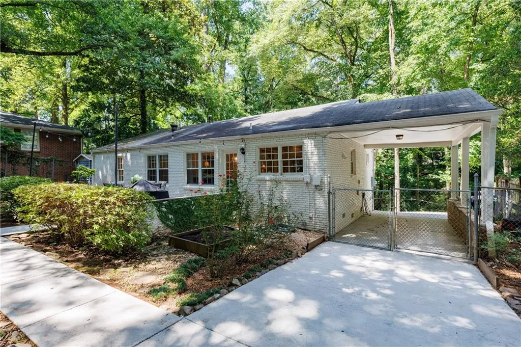 Ranch-style home featuring brick siding, a carport, a gate, and driveway