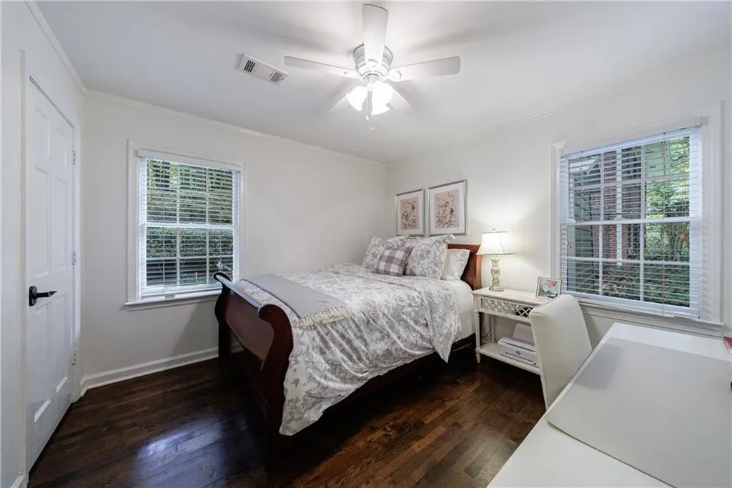 Bedroom featuring dark wood-style flooring, multiple windows, ornamental molding, and a ceiling fan