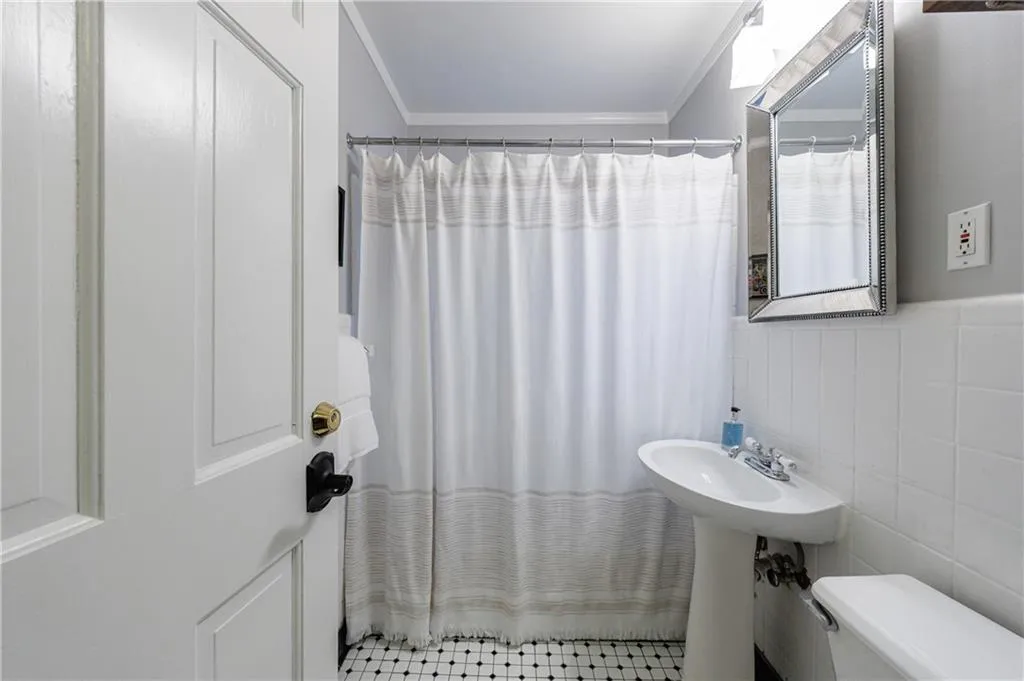Bathroom featuring crown molding, tile walls, and a shower with curtain