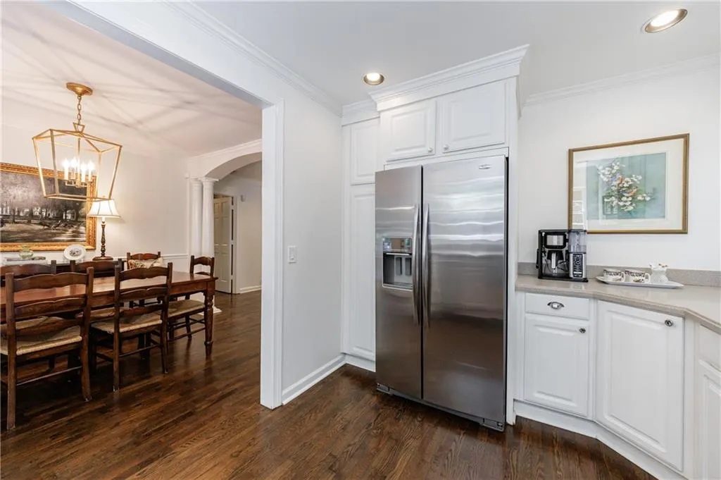 Kitchen with arched walkways, stainless steel refrigerator with ice dispenser, dark wood-type flooring, light countertops, and white cabinets