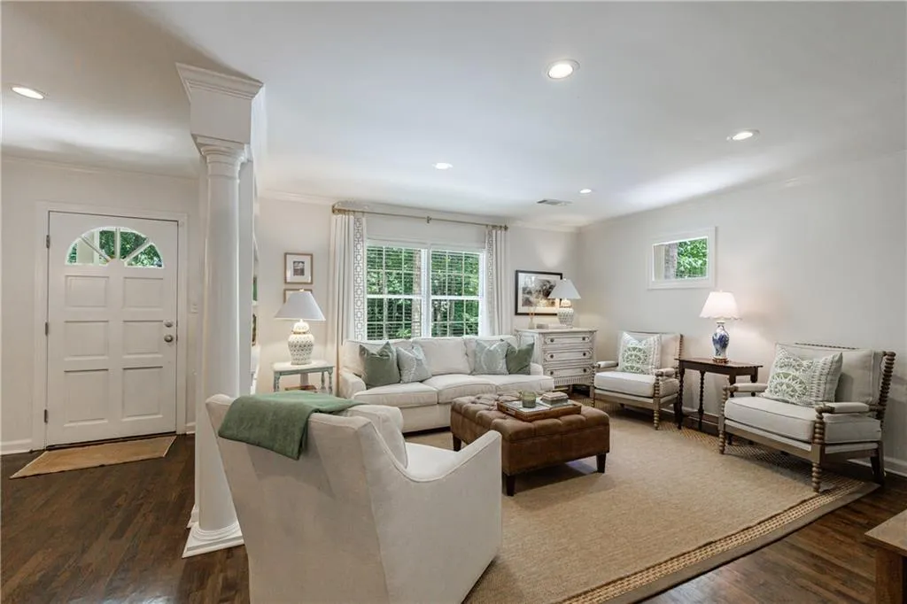 Living area with ornate columns, ornamental molding, dark wood-style flooring, and recessed lighting