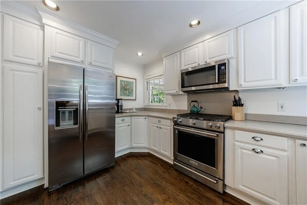 Kitchen featuring stainless steel appliances, white cabinetry, dark wood finished floors, light countertops, and recessed lighting