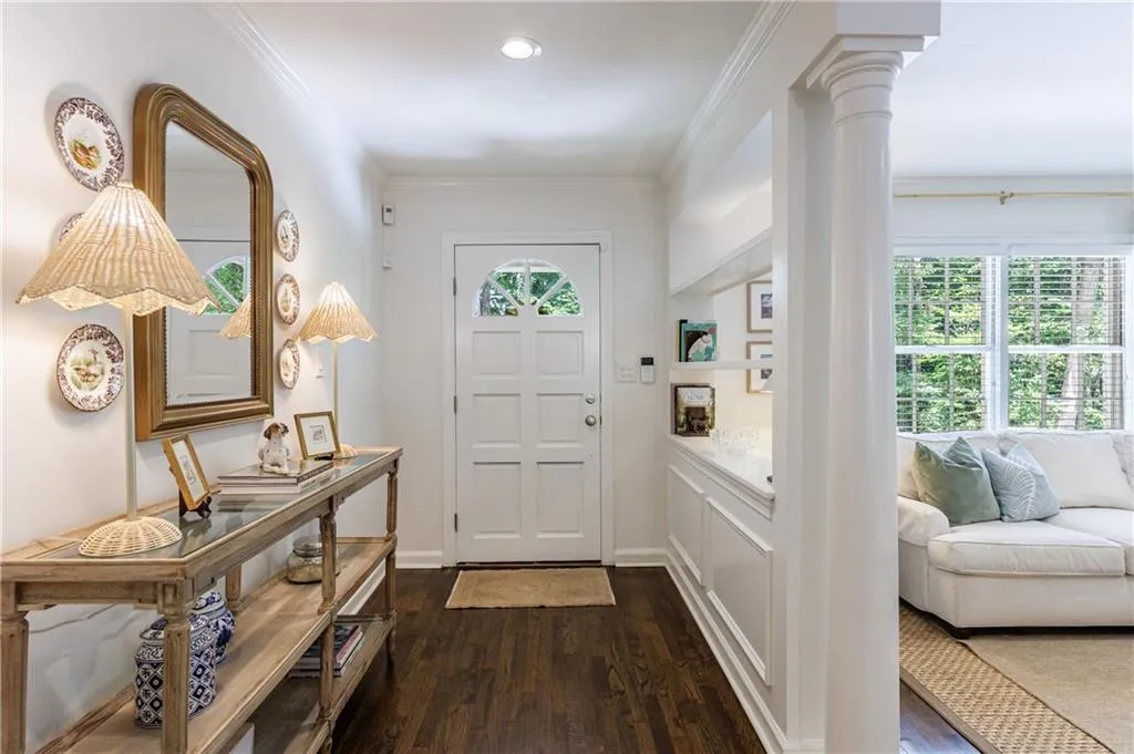 Entryway featuring dark wood-style flooring, decorative columns, healthy amount of natural light, and crown molding