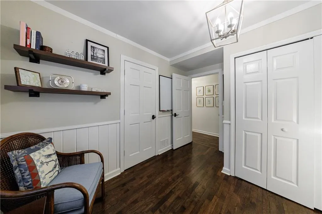 Living area featuring a chandelier, dark wood finished floors, and crown molding