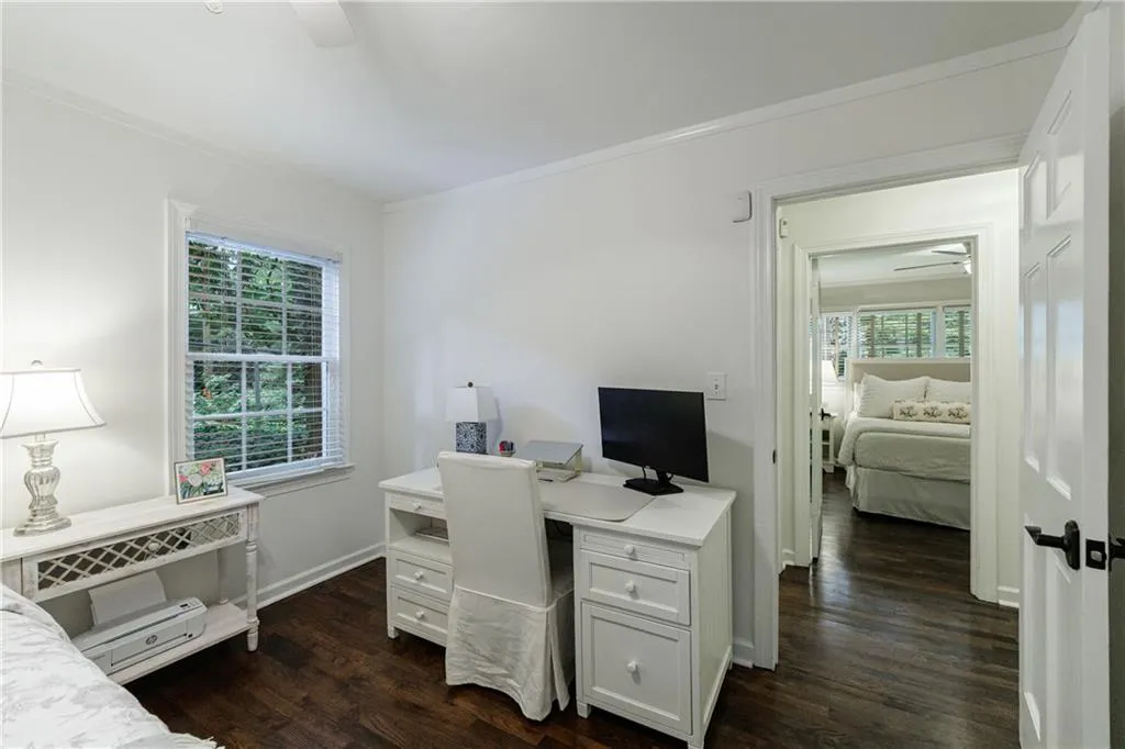 Home office with a ceiling fan, healthy amount of natural light, dark wood finished floors, and crown molding