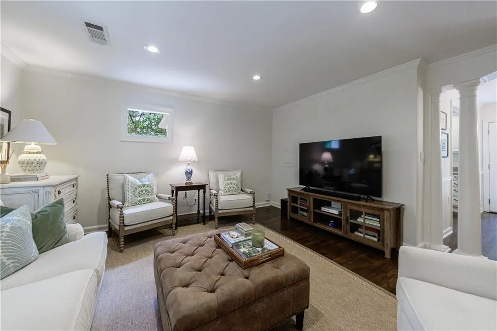 Living room featuring crown molding, recessed lighting, wood finished floors, and decorative columns