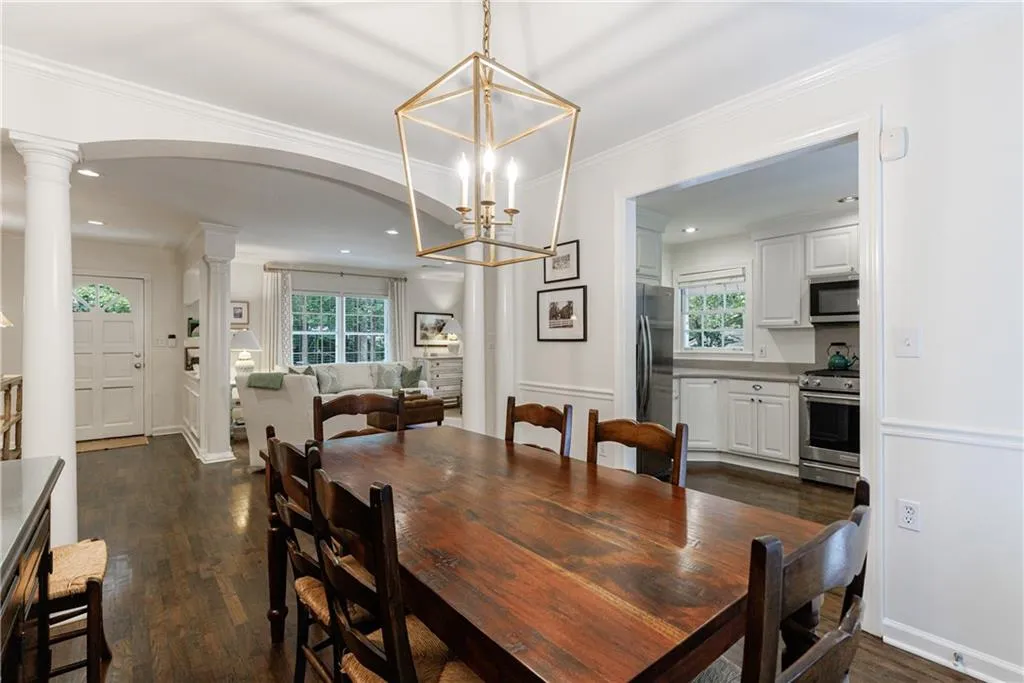 Dining area featuring ornate columns, dark wood-style floors, a chandelier, recessed lighting, and crown molding