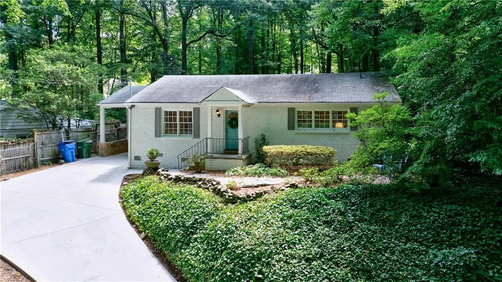 View of front of house featuring driveway, brick siding, and a carport