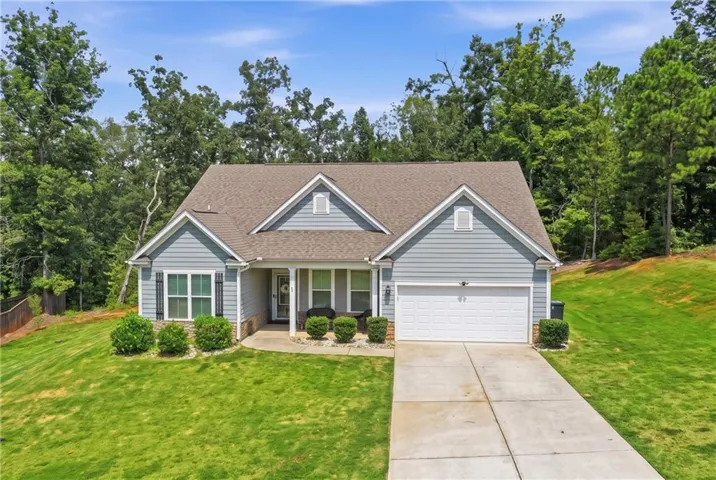 Light blue siding exterior with stone accents, covered front entry, two-car garage, and a concrete driveway