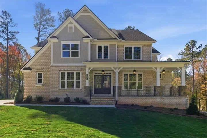 Two-story residence featuring light-colored brick and shingle siding