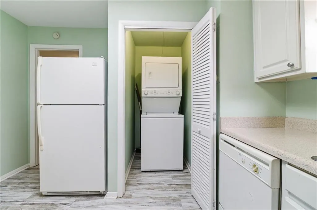 Laundry area with stacked washer / dryer and light wood-style flooring