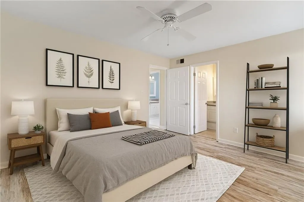 Bedroom with light wood-style floors, a ceiling fan, and ensuite bath
