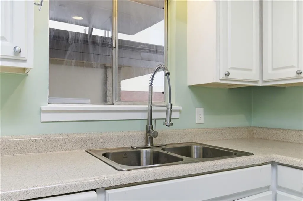 Kitchen with white cabinetry and light stone countertops