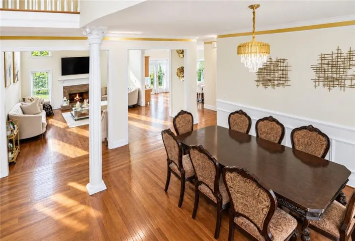 Hardwood flooring throughout, a decorative column, and a fireplace with a stone surround
