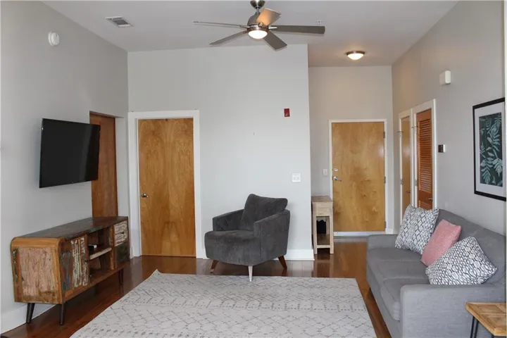 Open living area featuring wood-finish flooring, a ceiling fan with integrated lighting, and light gray walls