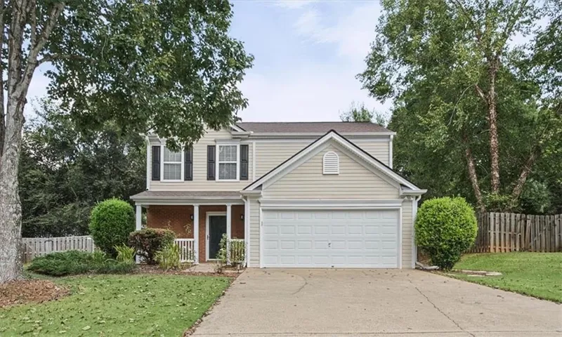 Two-story exterior with light-colored siding, covered front porch, and an attached garage
