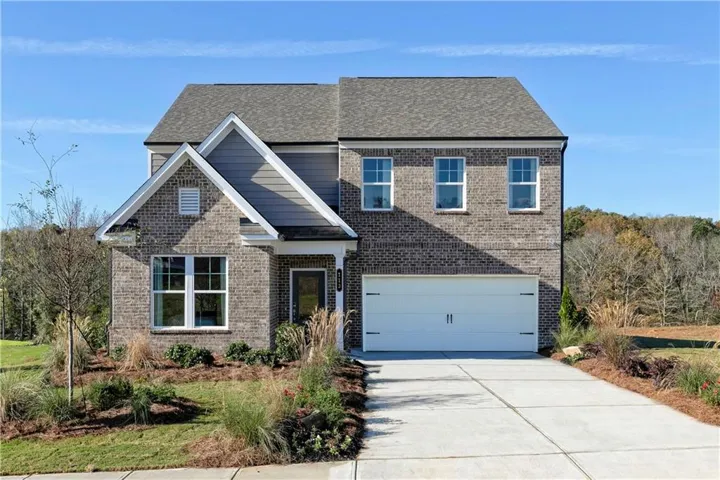 View of front facade featuring driveway, brick siding, an attached garage, and a shingled roof
