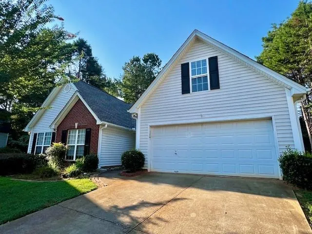 White siding exterior with brick accents, attached garage, and gabled rooflines