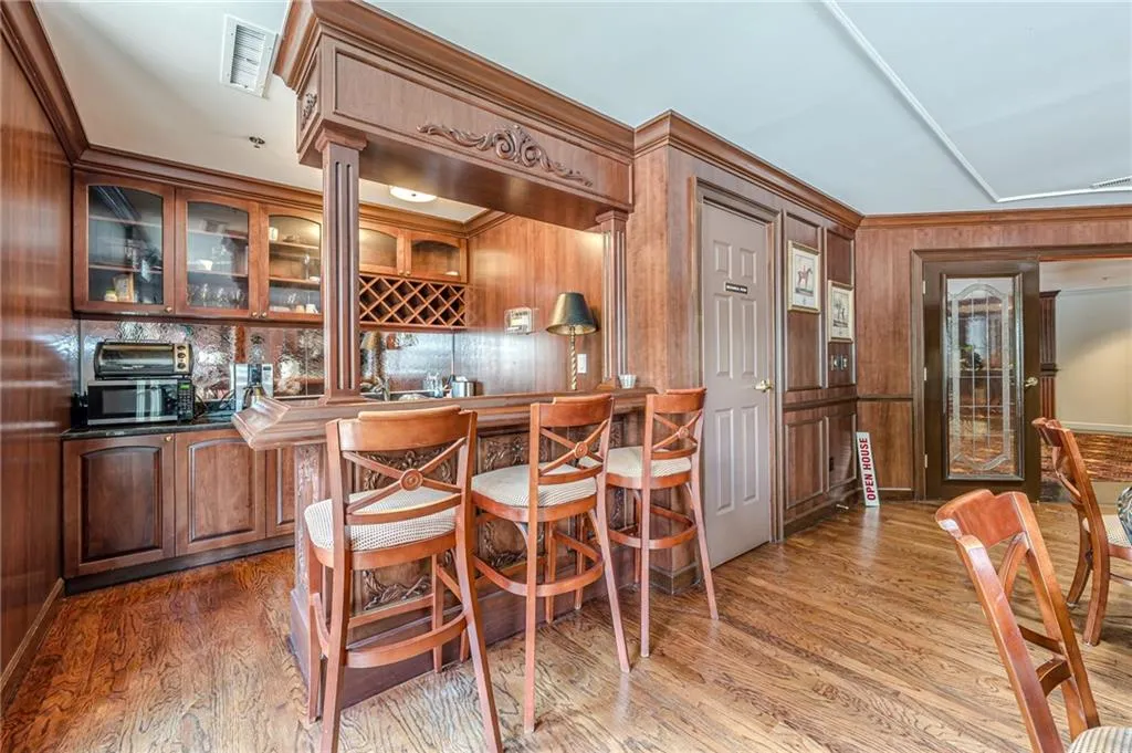 Indoor bar featuring wood finished floors, wooden walls, and ornamental molding
