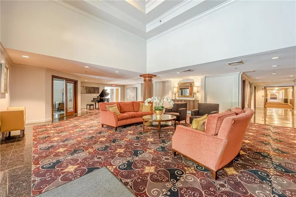 Living room with decorative columns, recessed lighting, crown molding, and a high ceiling