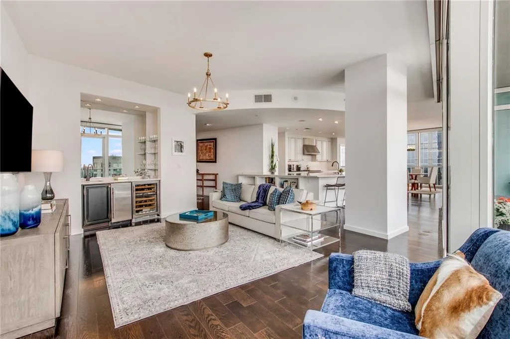 Living area featuring dark wood-style flooring, beverage cooler, a dry bar, and a chandelier