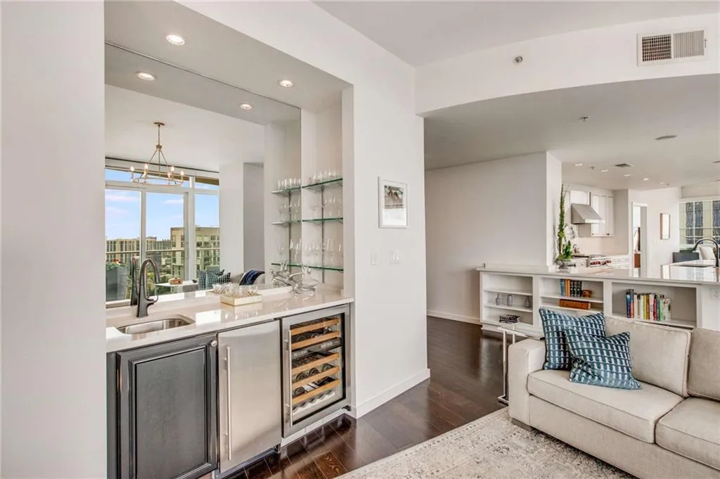 Indoor wet bar featuring light stone countertops, wine cooler, recessed lighting, dark wood-style flooring, and pendant lighting