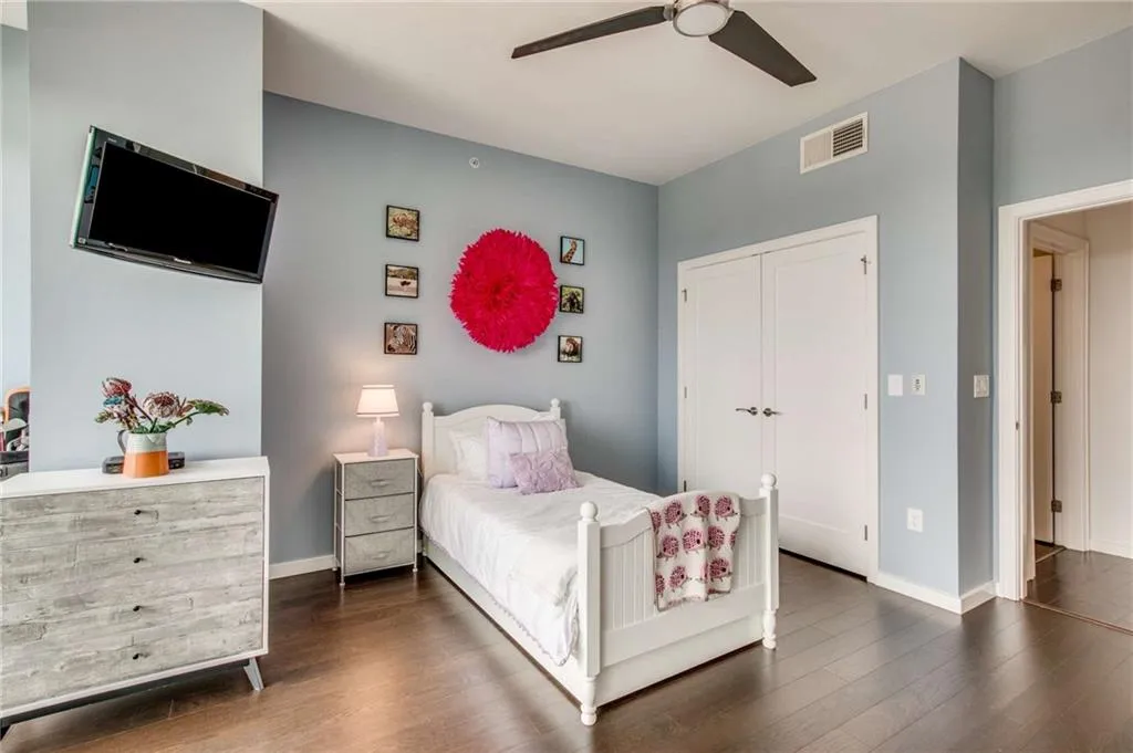 Bedroom with dark wood-type flooring, ceiling fan, and a closet