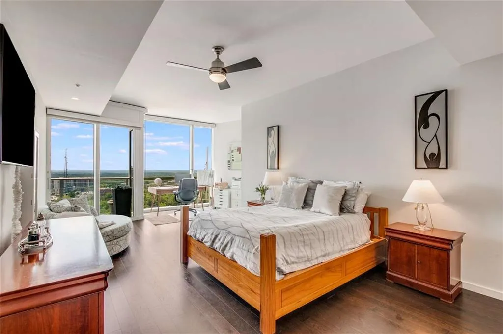 Bedroom featuring a wall of windows, access to outside, a ceiling fan, and dark wood finished floors