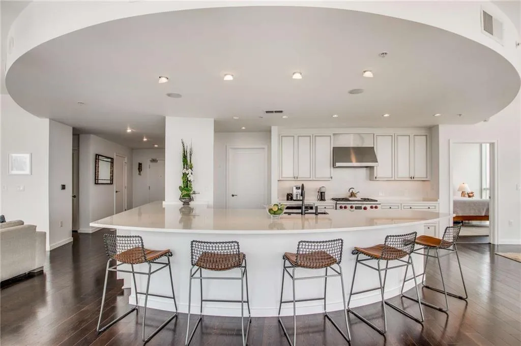 Kitchen featuring a large island, a kitchen breakfast bar, white cabinets, dark wood-style flooring, and extractor fan