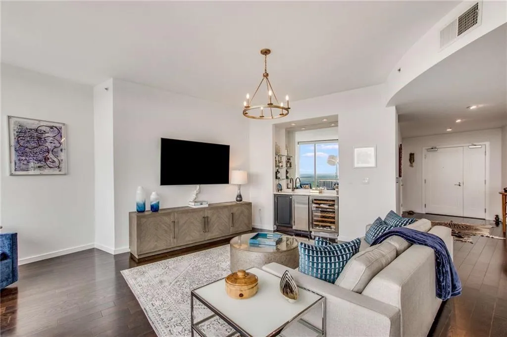 Living area with dark wood-type flooring, beverage cooler, a chandelier, and recessed lighting