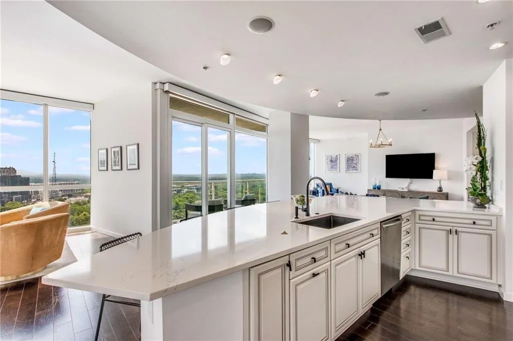 Kitchen with open floor plan, dark wood-type flooring, light stone countertops, a peninsula, and a chandelier