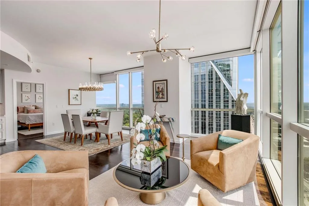 Living area featuring expansive windows, dark wood-type flooring, and a chandelier