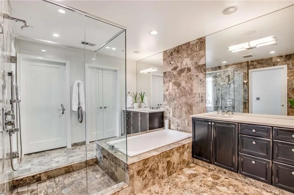 Bathroom featuring two vanities, a bath, a shower stall, and tile walls