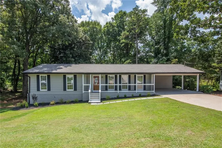 Ranch-style exterior with a covered front porch, carport, and a concrete driveway