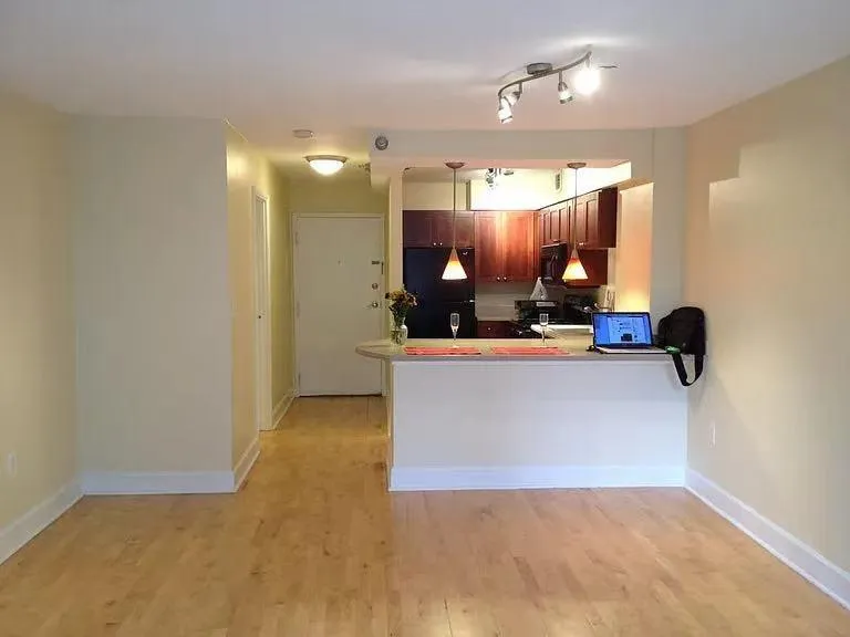 Kitchen with freestanding refrigerator, light wood-type flooring, decorative light fixtures, light countertops, and a peninsula
