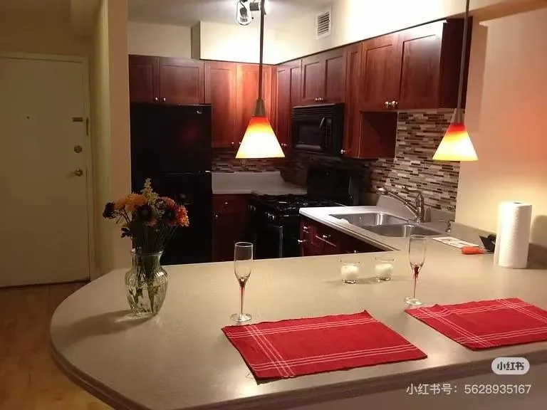 Kitchen featuring black appliances, backsplash, light countertops, and decorative light fixtures