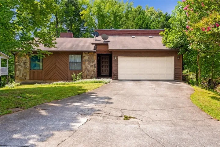 Wood siding exterior with stone accents, attached garage, and a concrete driveway