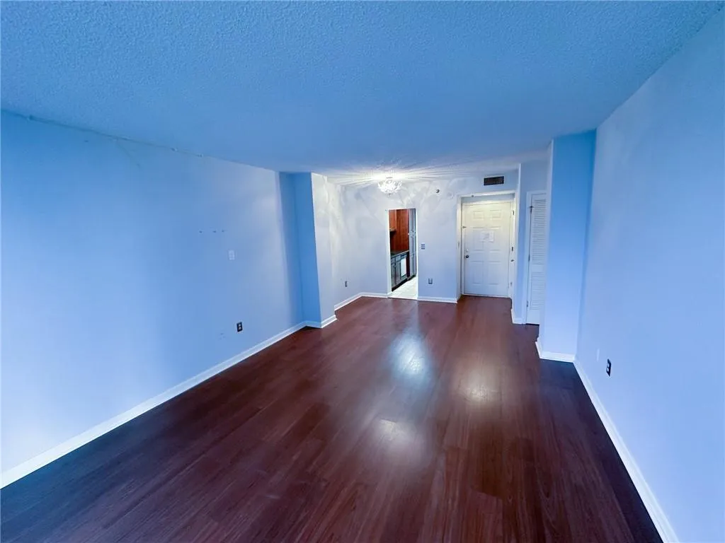 Unfurnished room with a textured ceiling, a chandelier, and dark wood finished floors