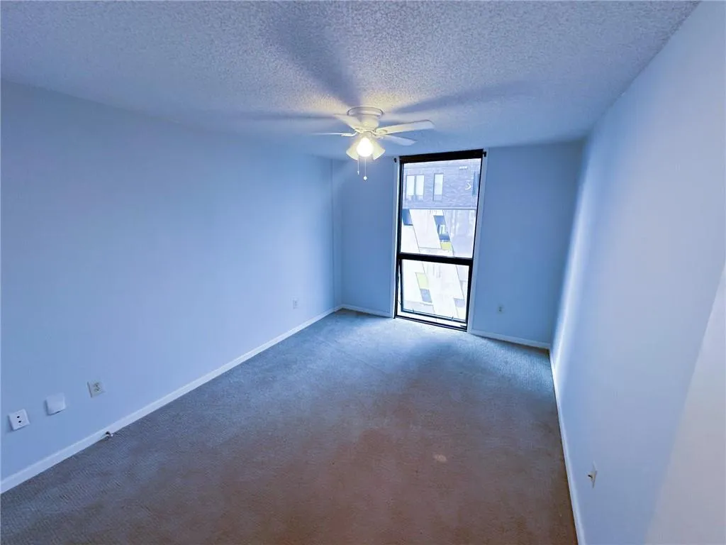 Empty room with carpet floors, a textured ceiling, and a ceiling fan
